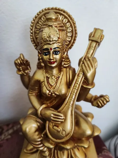 Goldfarbene Saraswati-Figur mit Saiteninstrument in der Praxis