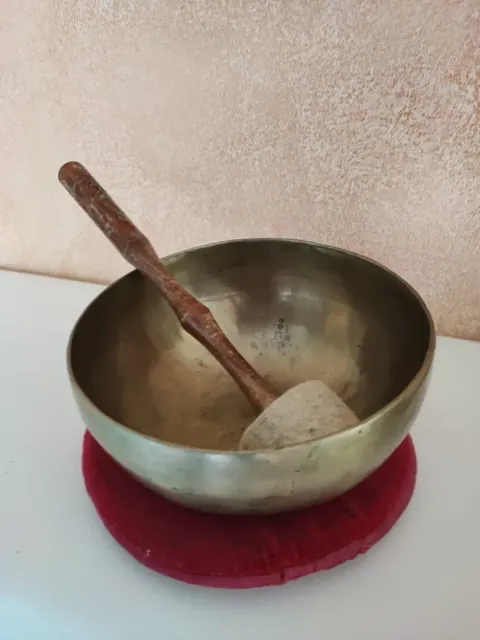 Klangschale aus Metall mit Kl auf rotem Kissen